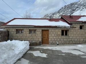 una casa de piedra con una puerta en la nieve en cozy apartments kazbegi, en Kazbegi