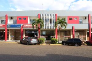two cars parked in front of a building with palm trees at RADAR PÁLACE HOTEL in Caculé