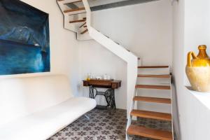 a living room with a staircase and a white chair at Iancura - B&B di design a Salina in Santa Marina Salina