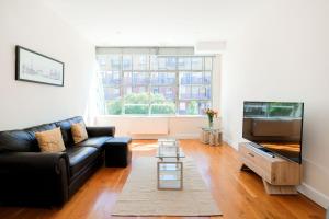 a living room with a black couch and a tv at Lovely 2 bed flat in canal side gated development in London
