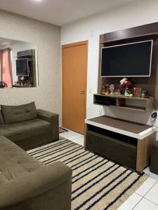 een woonkamer met een bank en een grote televisie bij Um apartamento bem aconchegante! in Palmas