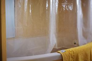 a shower curtain on a bath tub with a yellow towel at Ferienwohnung Bambushain Nieder-Olm in Nieder-Olm