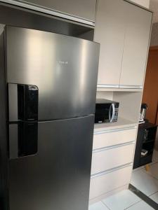 einem Kühlschrank aus Edelstahl in einer Küche neben einer Mikrowelle in der Unterkunft Um apartamento bem aconchegante! in Palmas