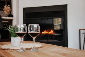 two glasses of wine sitting on a table with a fireplace at Suite 204 - Destination Mont-Orford in Magog-Orford