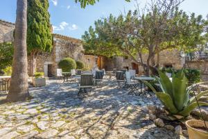 a patio with chairs and tables and trees at Finca Es Castell in Binibona