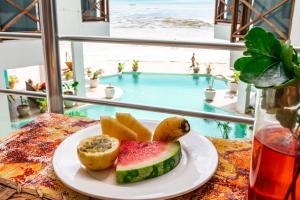 um prato de fruta numa mesa em frente a uma piscina em Pili Pili Tropical Island em Jambiani