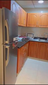 a kitchen with wooden cabinets and a stainless steel refrigerator at عجمان in Ajman 