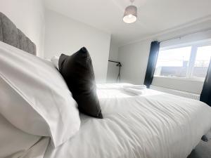 a bedroom with a large white bed with black pillows at York House by Blue Skies Stays in Stockton-on-Tees
