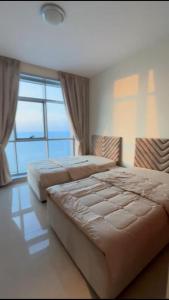two beds in a bedroom with a large window at عجمان in Ajman 