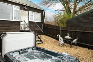 um quintal com uma banheira de hidromassagem e dois pássaros em Dreamwood - Woodland Cottage with Private Hot Tub em Blandford Forum