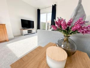 a vase of flowers on a table in a living room at York House by Blue Skies Stays in Stockton-on-Tees