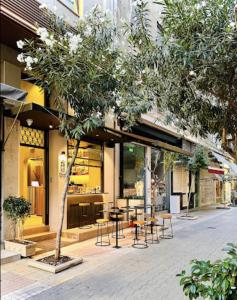 a building with tables and chairs in front of a store at DWELL - Elegant City Stay in Athens