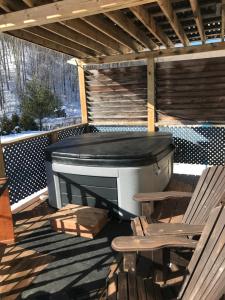 a hot tub and two chairs on a deck at Domaine de la Baie, Les Suites in Shawinigan