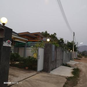 a house with a white door and a fence at Bann Sukjai in Kanchanaburi