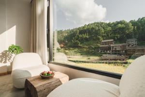 une chambre avec deux chaises et une fenêtre avec vue dans l'établissement 肇兴溪舍山堂 Creekside Inn, à Liping