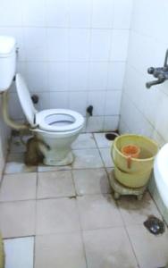 a bathroom with a toilet and a yellow bucket at Hotel Viren Plaza Inn Agra in Agra