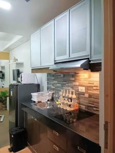 cocina con armarios blancos y encimera negra en A's Staycation -Trees Residences, en Manila