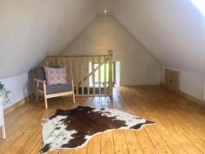 een zolderkamer met een stoel en een tapijt bij Old Stone Byre in Totaig