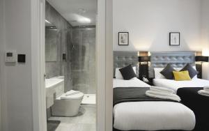 a bedroom with two beds and a bathroom with a shower at The 29 London in London