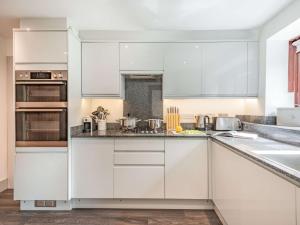 uma cozinha com armários brancos e electrodomésticos de aço inoxidável em 3 Bed in Winfrith Newburgh DC108 em Winfrith Newburgh