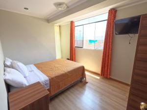 1 dormitorio con cama y ventana grande en Millpu Hostal, en Ayacucho