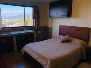 a bedroom with a bed and a large window at Hostal Casa San Fernando Tumbaco in Quito