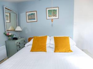 ein Schlafzimmer mit einem weißen Bett mit zwei gelben Kissen in der Unterkunft Pass The Keys Wilf's Barn, Wedmore a romantic cottage for two in Wedmore