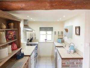 a kitchen with white counter tops and a window at Pass The Keys Wilf's Barn, Wedmore a romantic cottage for two in Wedmore