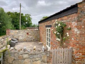 a brick building with a patio and a fence at Pass The Keys Wilf's Barn, Wedmore a romantic cottage for two in Wedmore