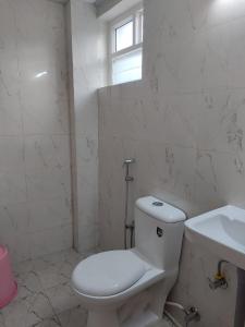 a white bathroom with a toilet and a sink at Shree Skanthas inn in Palni