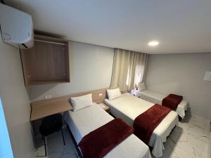 um quarto de hotel com duas camas e uma secretária em Hotel Fênix Belenzinho em São Paulo