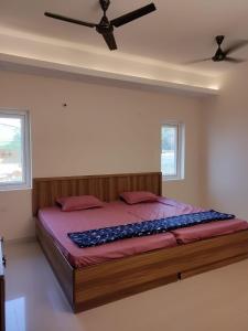 a bed in a bedroom with a ceiling fan at Shree Skanthas inn in Palni