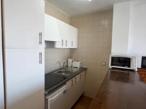 エンプリアブラバにあるBasic Comfort Apartment Gran Reserva 0078の白いキャビネット、シンク、電子レンジ付きのキッチンが備わります。
