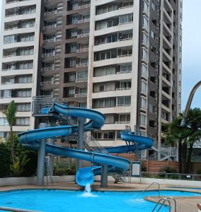 eine Wasserrutsche in einem Pool mit einem Gebäude in der Unterkunft Departamento Aquamar in Viña del Mar