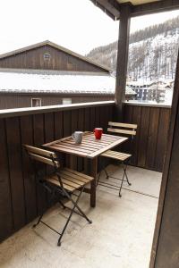 einen Holztisch und Stühle auf einem Balkon mit Schnee in der Unterkunft Pont du Verdon - 207 - Vue montagne 4 pers in Allos