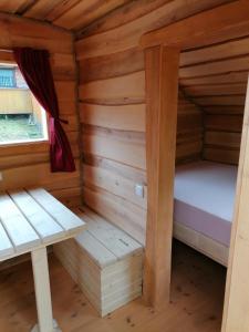 Cette chambre se trouve dans une cabane en rondins dotée d'un lit et d'un banc. dans l'établissement Wolpertinger | Camping-Aach, à Oberstaufen