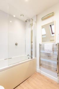 a bathroom with a shower and a tub at 1 Ruscon Cottage in Brancaster