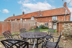 a table and chairs in front of a house at 1 Ruscon Cottage in Brancaster