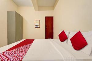 a bedroom with a large white bed with red pillows at Hotel O Trident Inn in Coimbatore +25 photos