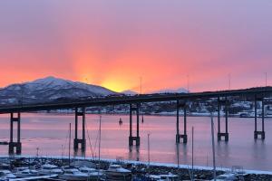 uma ponte sobre uma massa de água com um pôr-do-sol em Leilighet ved porten til Senja. em Finnsnes