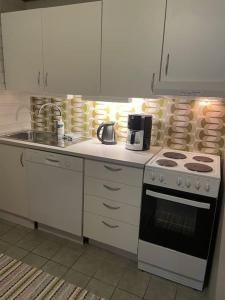 uma cozinha com armários brancos e um forno com placa de fogão em Leilighet ved porten til Senja. em Finnsnes