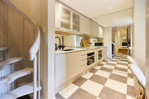 a kitchen with white cabinets and a checkered floor at The Kensington Place - Stylish 1BDR Flat in London