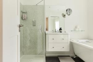 a white bathroom with a shower and a sink at The Kensington Place - Stylish 1BDR Flat in London
