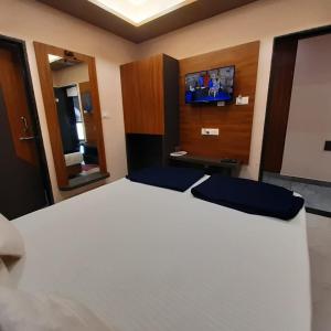a bedroom with a white bed and a tv at Hotel Purushottam in Dwarka