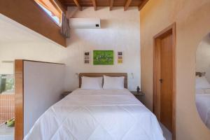una camera da letto con un letto con lenzuola bianche e una finestra di Villa Serena Eco-Lodges a Garopaba