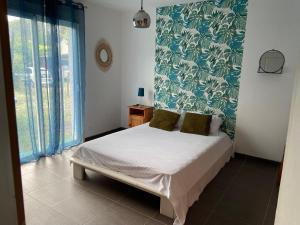 een slaapkamer met een bed met groen en wit behang bij Villa proche bassin 10 personnes in Mios