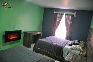 1 dormitorio con 2 camas, chimenea y ventana en Departamentos - Cabañas Sias, en Creel