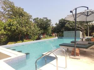 a swimming pool with a table and an umbrella at Habitus - Mandrem in Mandrem