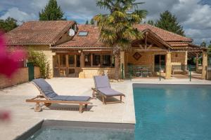 ein Haus mit 2 Liegestühlen und einem Pool in der Unterkunft Maison Périgourdine avec piscine in Montignac