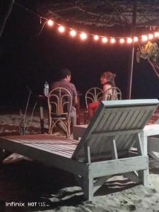 Locaroc的住宿－Akoya Beach Park and Cottages，男人和女人在晚上坐在野餐桌旁